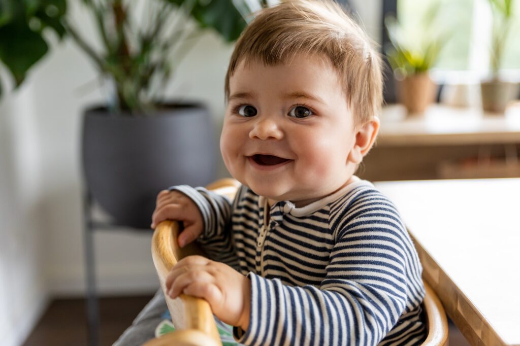 Happy 1 year old boy sitting in baby chair