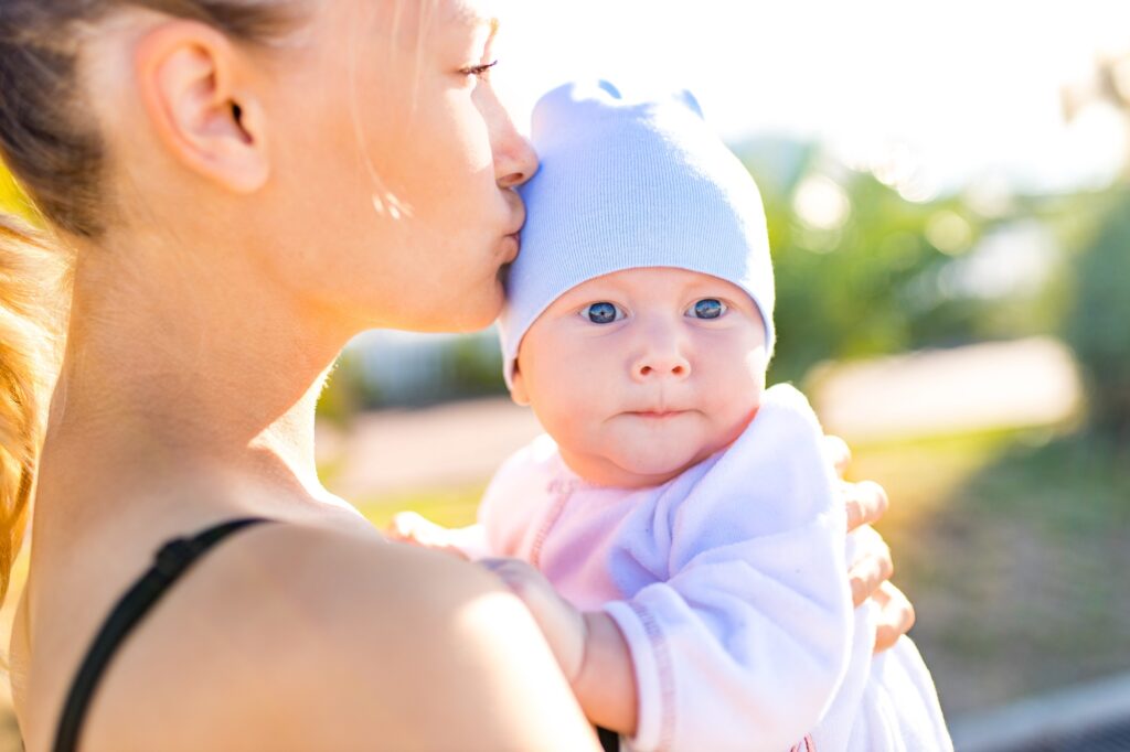 happy blonde woman kissind and feelinf adore to her stroll new born kid